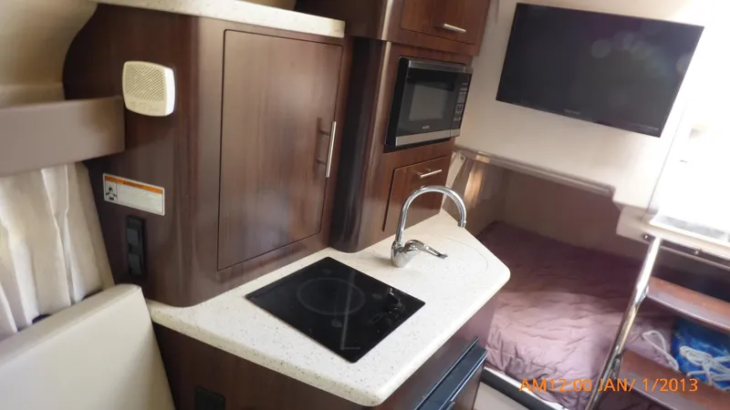 Slide: The Image of Interior of 2018 Regal 28 Express boat with kitchenette, stove, sink, and TV. - 34
