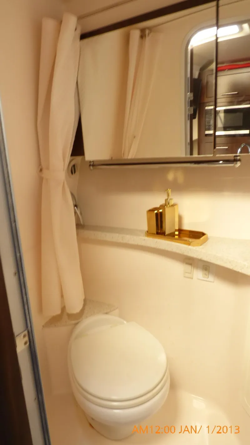 Slide: The Image of 2018 Regal 28 Express boat bathroom with toilet, mirror, and gold accents. - 38