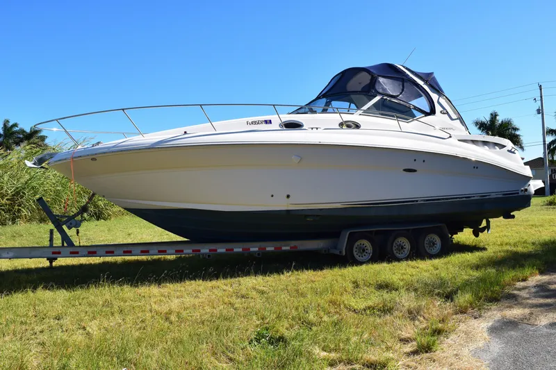 The Image of 2006 Sea Ray 320 Sundancer boat on trailer in grassy area. - 0