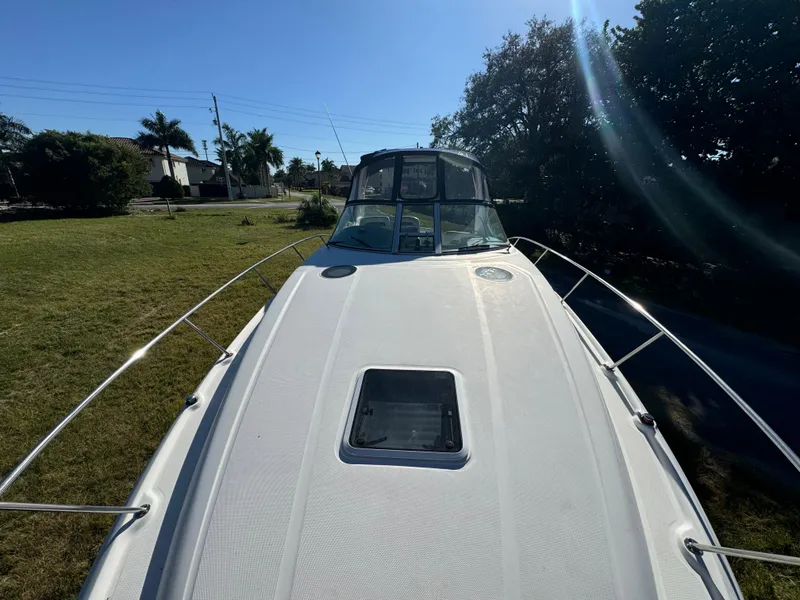 Slide: The Image of 2006 Sea Ray 320 Sundancer boat on grassy area under clear blue sky. - 13