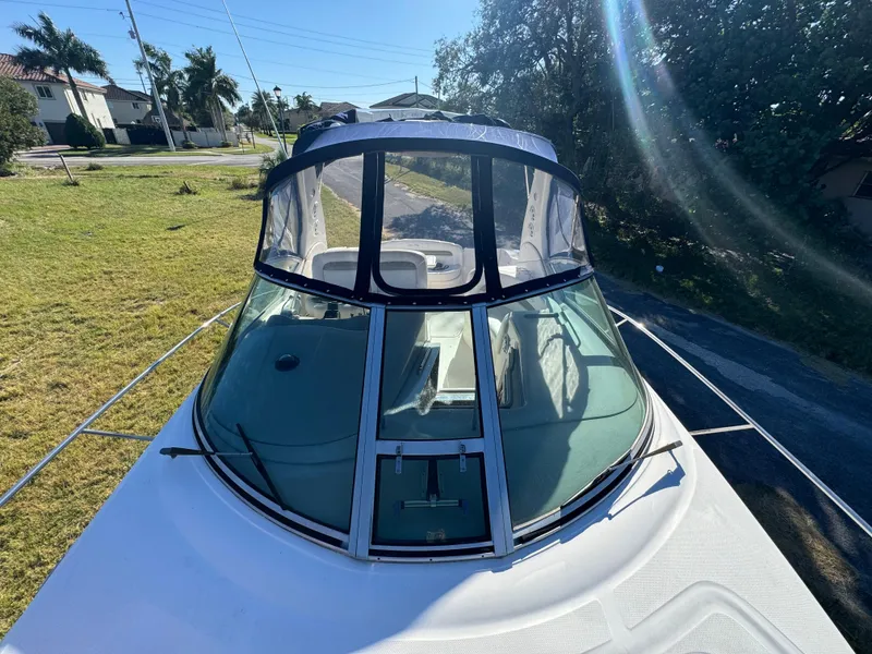 Slide: The Image of 2006 Sea Ray 320 Sundancer boat with clear canopy, parked on grass. - 16
