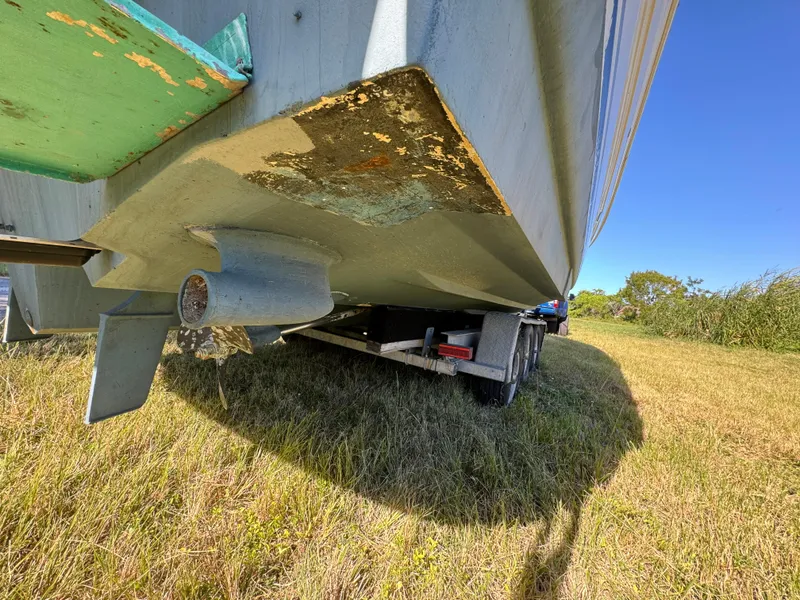 Slide: The Image of 2006 Sea Ray 320 Sundancer on trailer, showing hull and propeller, parked on grass. - 25
