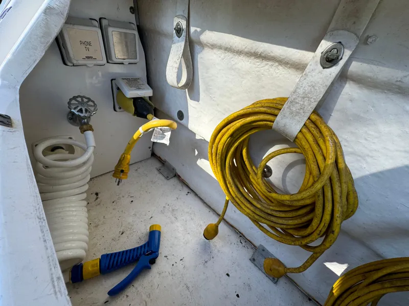 Slide: The Image of Storage compartment of 2006 Sea Ray 320 Sundancer with coiled yellow cable and hose. - 27
