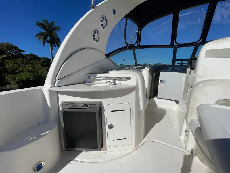 Slide: The Image of 2006 Sea Ray 320 Sundancer cockpit with sink and seating under clear blue sky. - 42