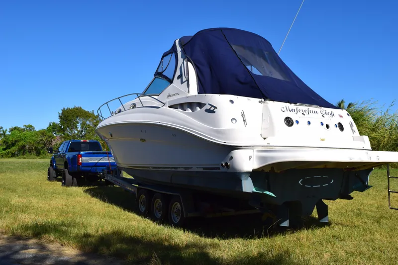 Slide: The Image of 2006 Sea Ray 320 Sundancer boat on trailer, parked on grass, with blue truck. - 5
