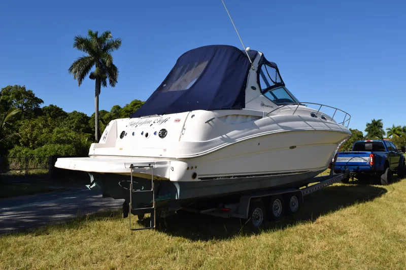 Slide: The Image of 2006 Sea Ray 320 Sundancer boat on trailer, parked on grass under clear blue sky. - 7