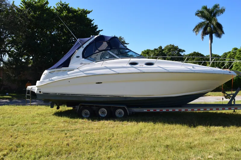 Slide: The Image of 2006 Sea Ray 320 Sundancer boat on trailer, parked on grass with trees in background. - 8