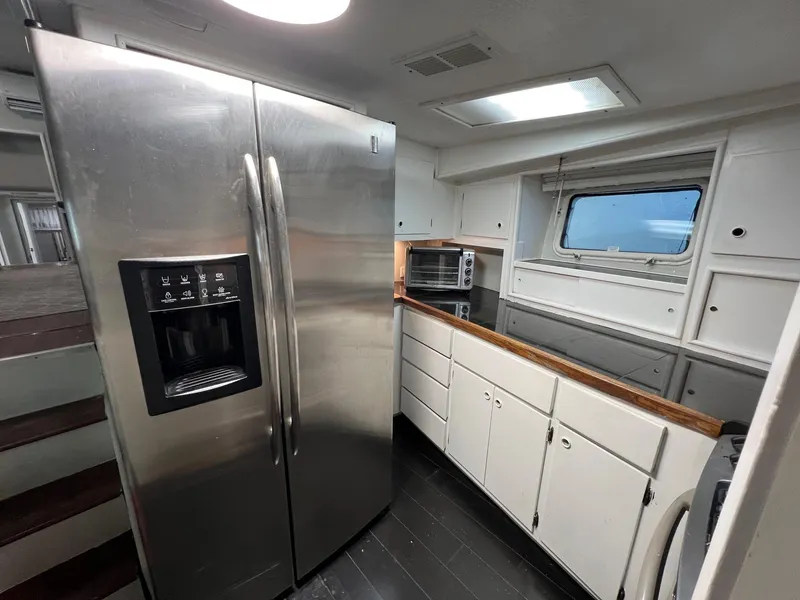 Slide: The Image of 1975 Hatteras 58 Motor Yacht kitchen with stainless steel fridge and white cabinetry. - 18