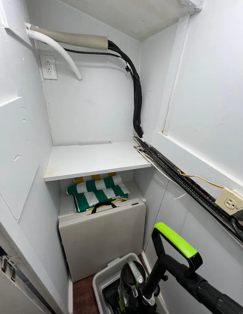 Slide: The Image of Storage area in a 1975 Hatteras 58 Motor Yacht with cleaning supplies and folded chairs. - 26