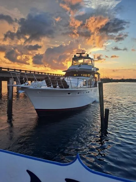 The Image of 1977 Bertram 58 Motor Yacht at sunset, docked near a bridge. - 0