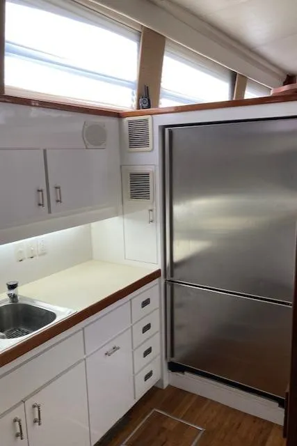 Slide: The Image of 1977 Bertram 58 Motor Yacht kitchen with stainless steel fridge and white cabinetry. - 15