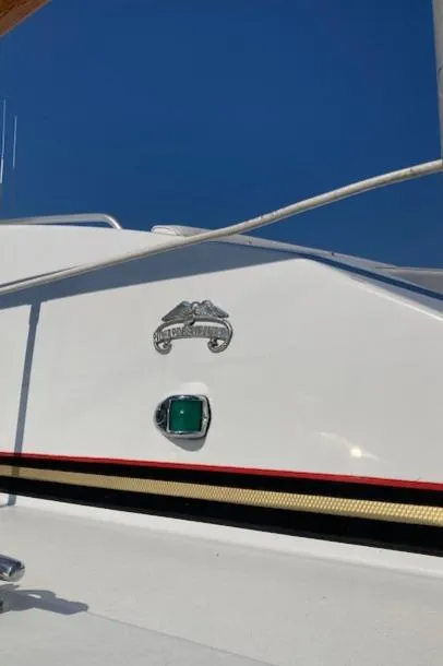 Slide: The Image of 1977 Bertram 58 Motor Yacht exterior detail with emblem and light against blue sky. - 2