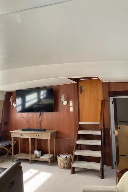 Slide: The Image of Interior of 1977 Bertram 58 Motor Yacht with TV, wooden stairs, and console table. - 5