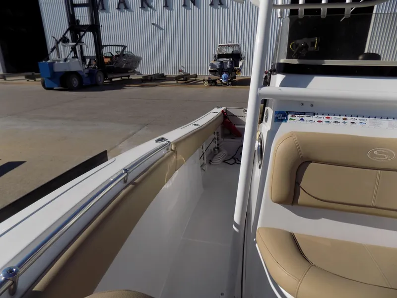 Slide: The Image of 2017 Sportsman Heritage 251 Center Console boat interior with tan seating and marina background. - 18