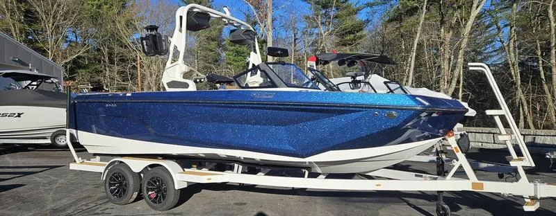 Slide: The Image of 2025 Nautique Super Air Nautique GS22 boat on trailer, blue exterior, parked outdoors. - 2