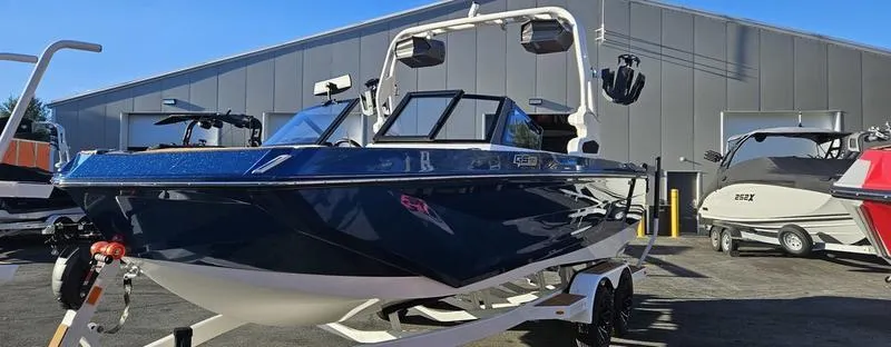 Slide: The Image of 2025 Nautique Super Air Nautique GS22 boat on trailer, parked outside a modern building. - 5