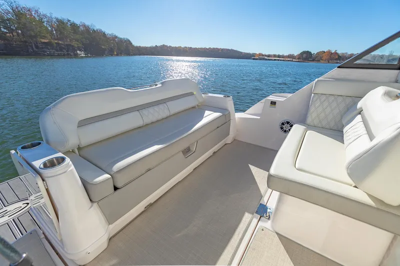 Slide: The Image of 2021 Regal 36 Grande Coupe boat interior with white seating, overlooking a serene lake. - 11