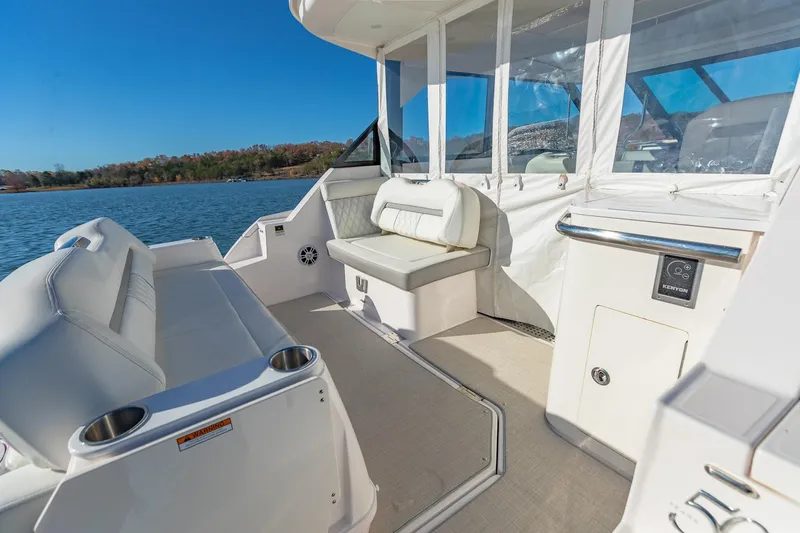 Slide: The Image of 2021 Regal 36 Grande Coupe boat interior with white seating and lake view. - 12