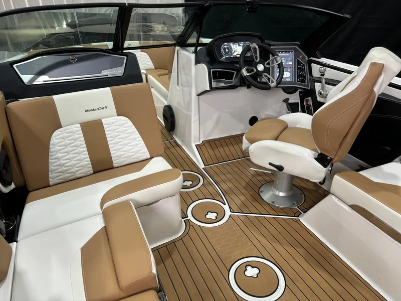 Slide: The Image of 2024 MasterCraft X24 boat interior with tan and white seating, modern dashboard, and wood-style flooring. - 13
