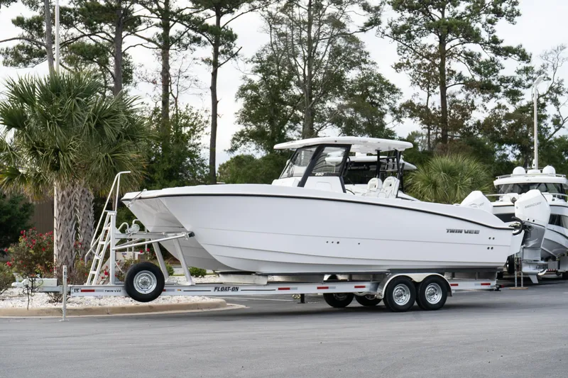 The Image of 2025 Twin Vee 280 GFX2 CC boat on trailer, parked near trees. - 1