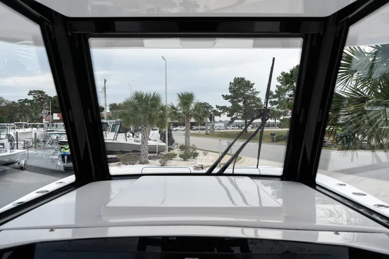 Slide: The Image of View from 2025 Twin Vee 280 GFX2 CC boat cockpit, showcasing marina and palm trees. - 28