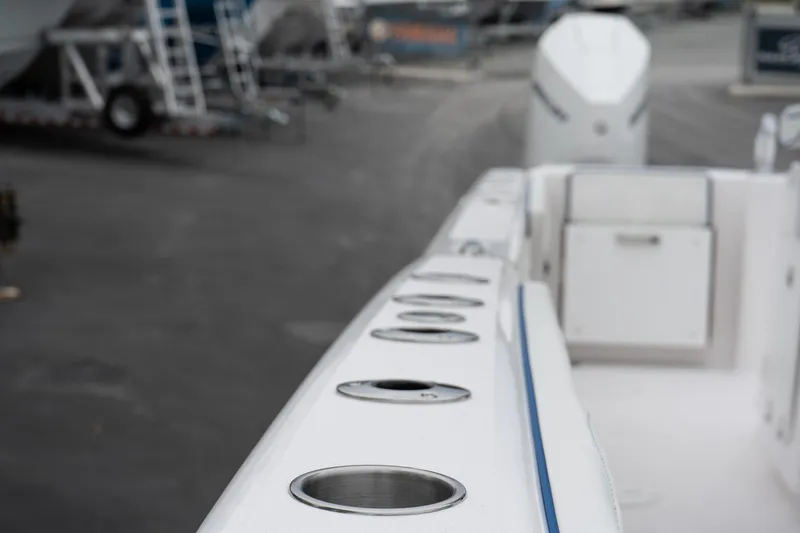 Slide: The Image of Twin Vee 280 GFX2 CC 2025 boat deck with rod holders, marina background. - 46