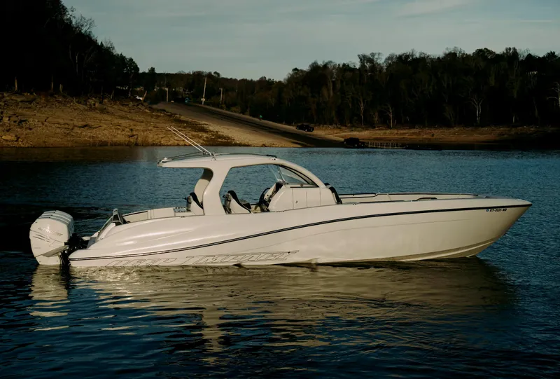 Slide: The Image of 2021 Deep Impact 399 Sport boat on calm water, near a wooded shoreline. - 28