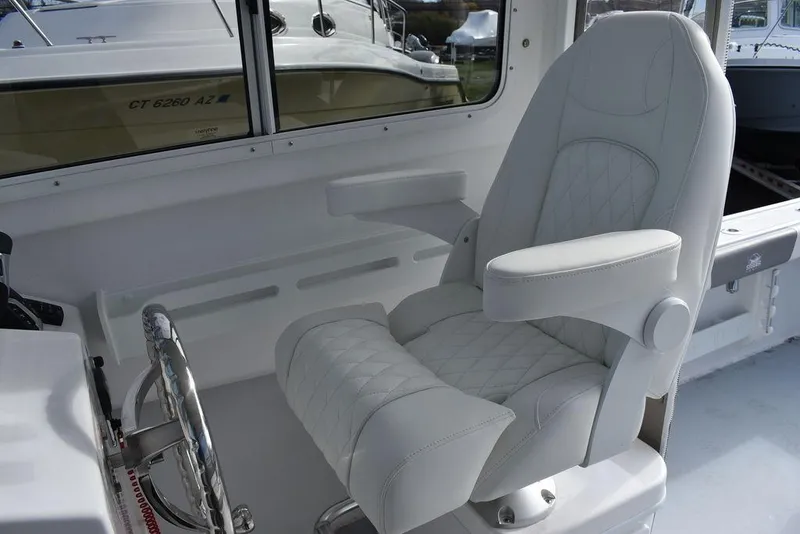 Slide: The Image of 2025 Steiger Craft 23 Miami boat interior with white captain's chair and steering wheel. - 17