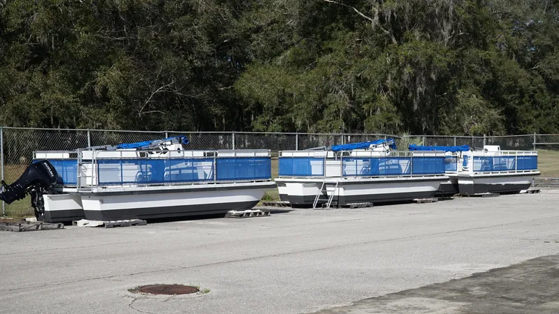 Slide: The Image of Three 2025 A&M Manufacturing Salty 23 boats parked on pavement near a fence. - 12