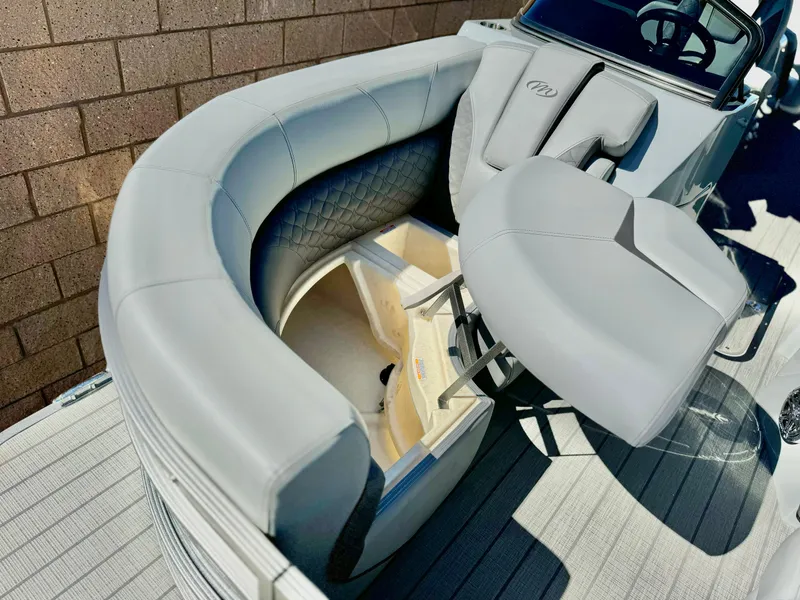 Slide: The Image of 2025 Manitou 23 LX RFXW boat interior with gray seating and storage compartment. - 19