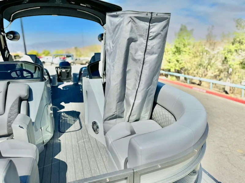 Slide: The Image of 2025 Manitou 23 LX RFXW pontoon boat interior with gray seating and privacy curtain. - 20