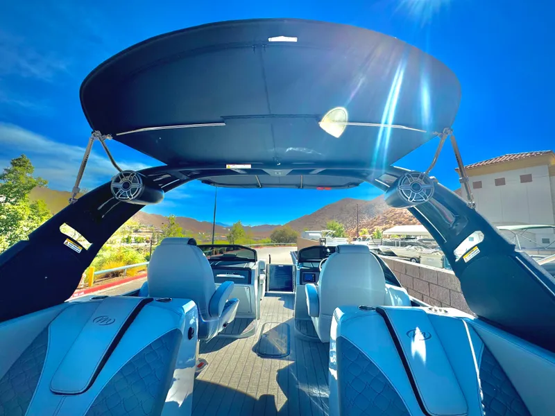 Slide: The Image of 2025 Manitou 23 LX RFXW pontoon boat interior with blue seating and canopy. - 24