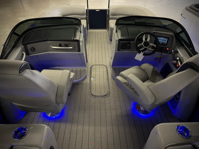 Slide: The Image of 2025 Manitou 23 LX RFXW boat interior with modern dashboard and ambient blue lighting. - 27