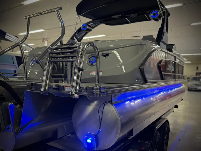 Slide: The Image of 2025 Manitou 23 LX RFXW pontoon boat with blue LED lights in showroom. - 29