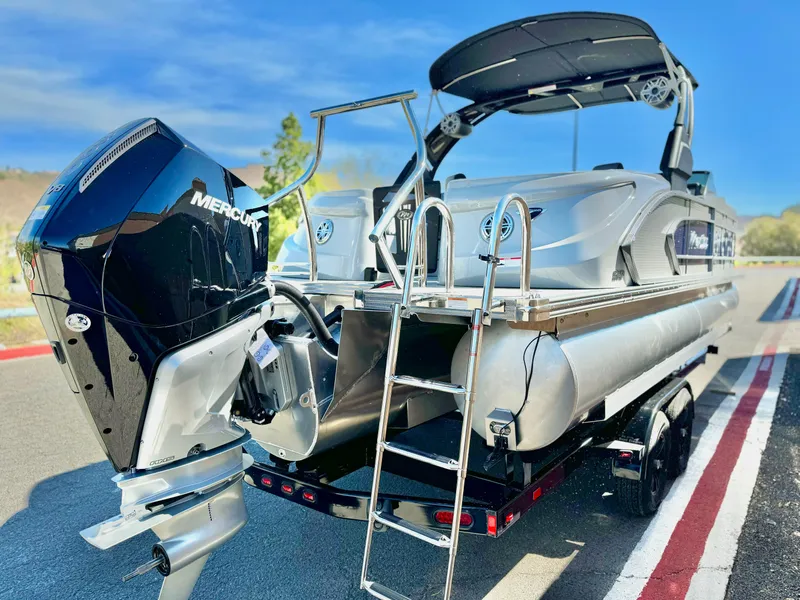 Slide: The Image of 2025 Manitou 23 LX RFXW pontoon boat with Mercury engine, parked on trailer. - 5