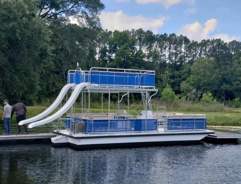 The Image of 2026 A&M Manufacturing Salty 28 DS pontoon boat with dual slides docked by a forested area. - 0