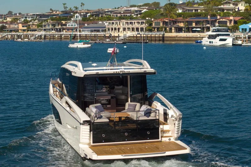 Slide: The Image of 2026 Absolute 48 Coupe yacht cruising near coastal homes. - 14
