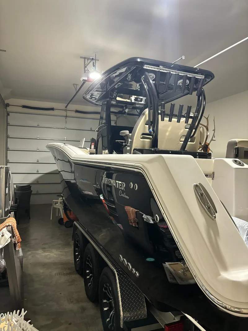Slide: The Image of 2022 Tidewater 320 CC Adventure boat in garage, black hull, dual engines. - 10