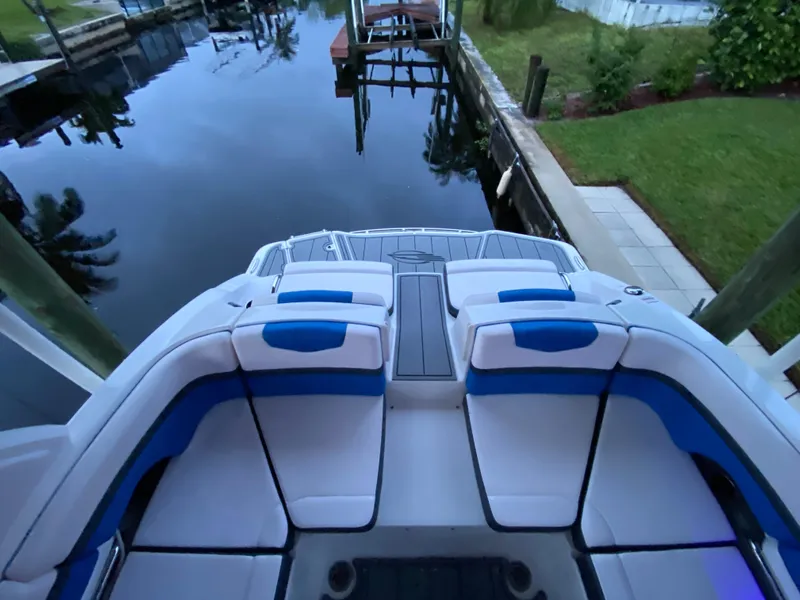 Slide: The Image of 2020 Chaparral 223 Vortex VRX boat interior with blue and white seating by a dock. - 21