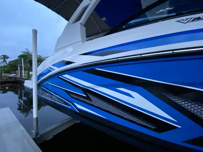 Slide: The Image of 2020 Chaparral 223 Vortex VRX boat with blue and white design docked by the water. - 4