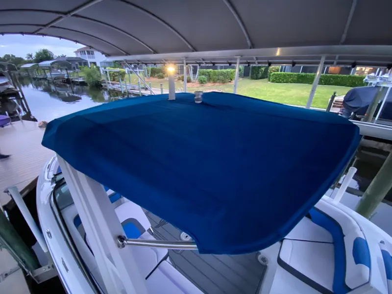 Slide: The Image of 2020 Chaparral 223 Vortex VRX boat with blue canopy docked in a covered marina. - 7