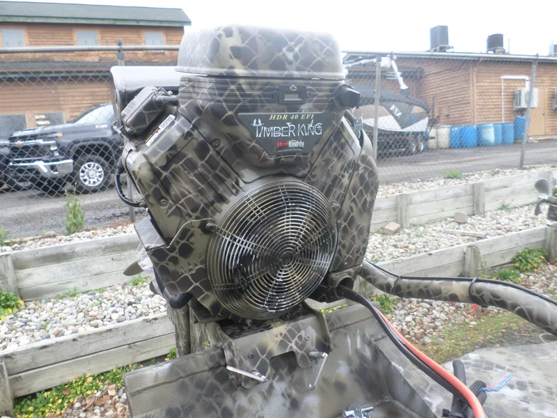 Slide: The Image of Camouflage-patterned engine of Excel 1860 Pro, 2025 model, outdoors near a wooden building. - 4