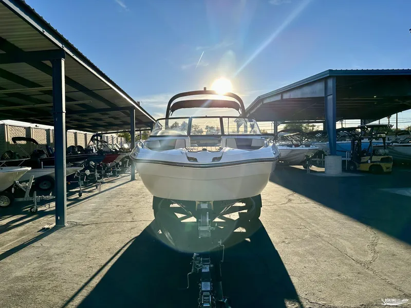 Slide: The Image of 2019 Yamaha AR240 boat in storage, sun setting behind, under covered area. - 2