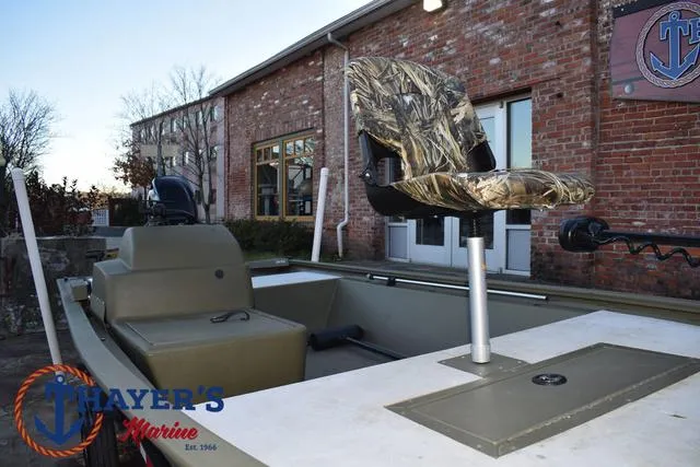 Slide: The Image of 2023 Tracker GRIZZLY® 1648 SC boat with camo seat, docked near brick building. - 27