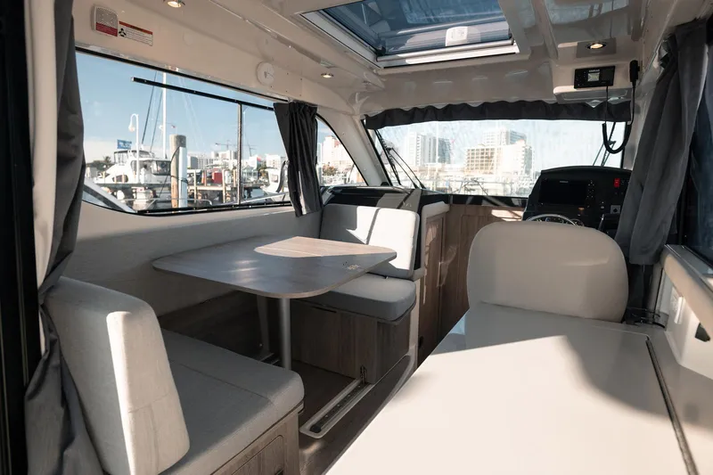 Slide: The Image of 2024 Bayliner Trophy T29EX interior with dining area and helm, featuring modern design and large windows. - 6
