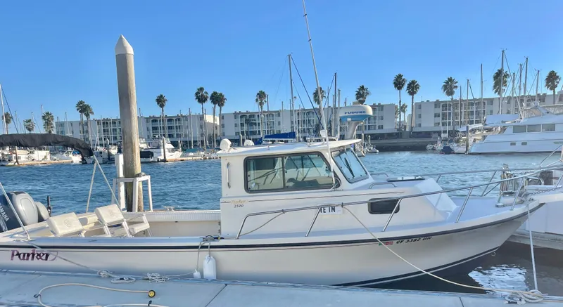 The Image of 2001 Parker 2502 boat docked at marina with palm trees and buildings in background. - 1