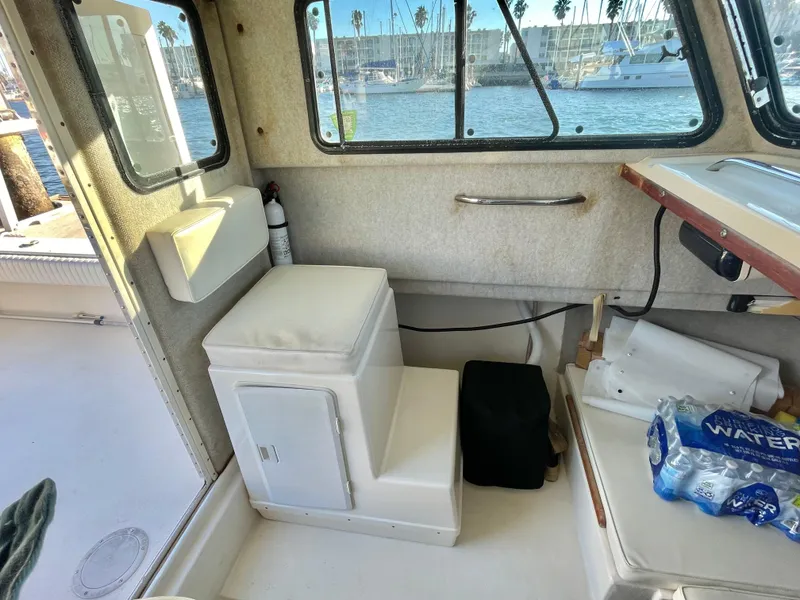 Slide: The Image of Interior of a 2001 Parker 2502 boat with seating and window view of marina. - 14
