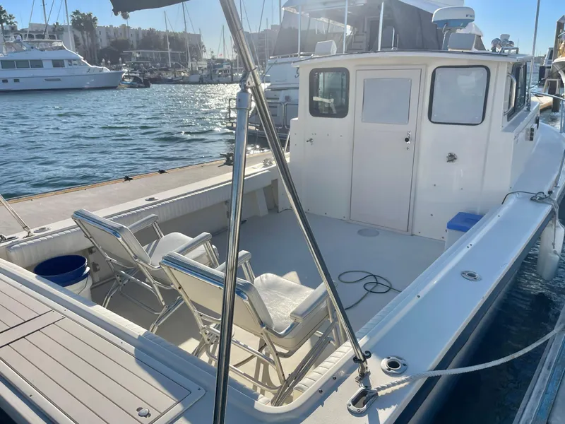 Slide: The Image of 2001 Parker 2502 boat docked, featuring spacious deck and seating, in a sunny marina setting. - 3