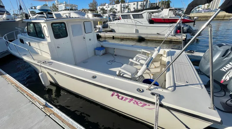 Slide: The Image of 2001 Parker 2502 boat docked at marina, featuring spacious deck and cabin. - 6