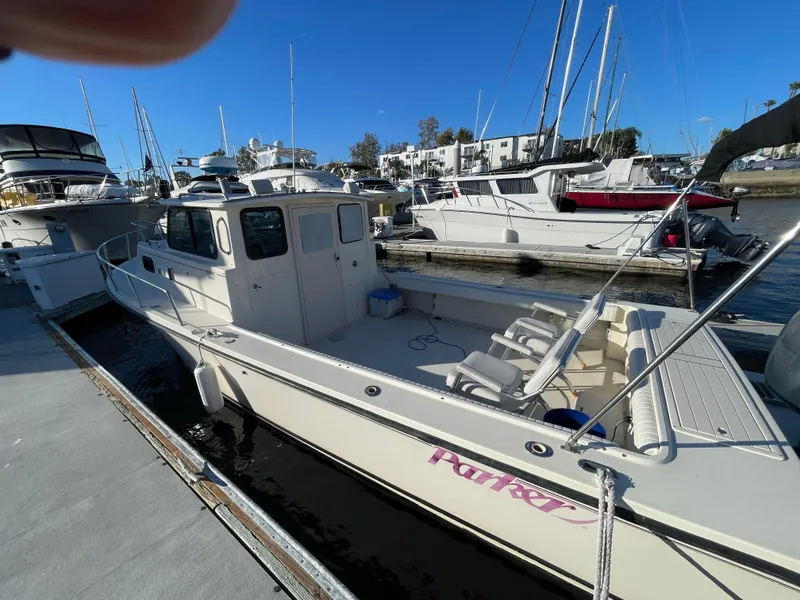 Slide: The Image of 2001 Parker 2502 boat docked at marina, surrounded by other vessels under clear blue sky. - 9